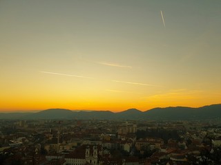 Sunset at the Schlossberg in Graz with a view of the west of Graz as well as mountains and trees - obrazy, fototapety, plakaty