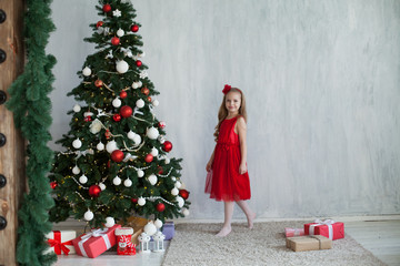 Little girl decorates Christmas tree gifts new year