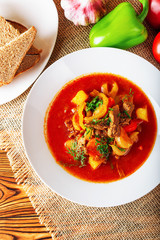 Hot beef hungarian  goulash soup with paprika, beef, potatoes, carrots, onion, pepper and herbs. Ingredients for dish.  Rustic background.