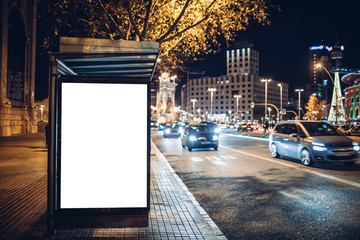 Night shot of a luminous advertising lightbox or display at a bus stop in Barcelona, Spain - obrazy, fototapety, plakaty