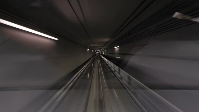 Automated people mover rush at tunnel, view through cabin windshield, driver window perspective. Time lapse shot, fast motion forward, dark walls seen in motion blur