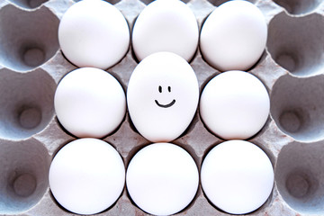 White eggs in a package on a blue background close-up view from above. 