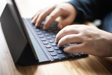 Man's hands working on the tablet at home, teleworking