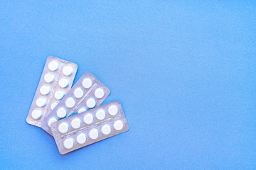 Aspirin in a blister on top. Vitamin C pills in a pack. White tablets in a blister on a blue background close-up with soft focus. 