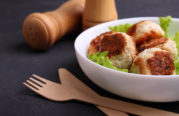 chicken cutlets with lettuce in a white plate on a black background
