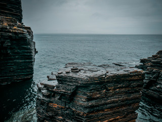 Scottish Coast, dark jagged rocks looking out to endless sea on an overcast day in the Highlands