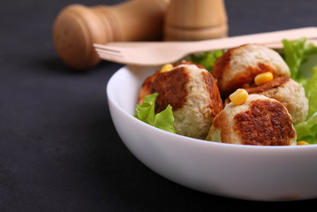 chicken cutlets with lettuce in a white plate on a black background