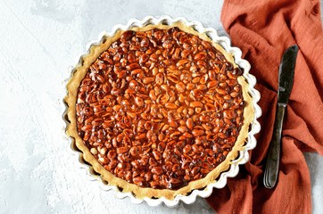 Tart with peanuts and condensed milk on a gray background