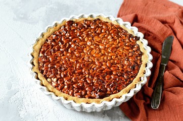 Tart with peanuts and condensed milk on a gray background