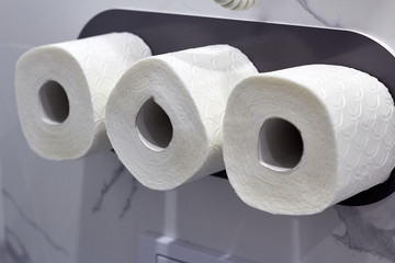 Three rolls of toilet paper hanging on the wall in the toilet room, cleanliness, hygiene