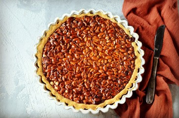 Tart with peanuts and condensed milk on a gray background
