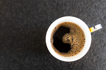 Coffee cup on black background. Top view. Coffee break during smart working at home. Black background