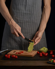 Chef man hands on cook  appetizer sandwiches with guacamole and tomatoes. healthy breakfast food, vegetarian food, diet. Gark style photo.