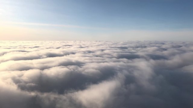 The view from the airplane window on the blue sky and white clouds. Flying a plane over fluffy beautiful white clouds. Daytime, the rays of the sun. Ultra HD stock footage. Travel concept. 4K