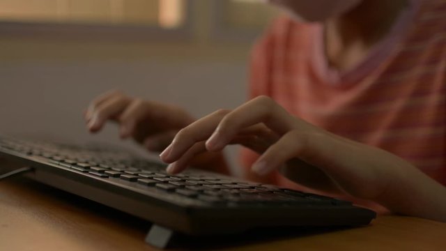 Close up hand of a girl typing on computer keyboard on the desk at home during COVID-19 outbreak situation. Study at home concept.