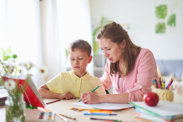 Mother tutor helps son to do lessons. correct the error in home lessons.