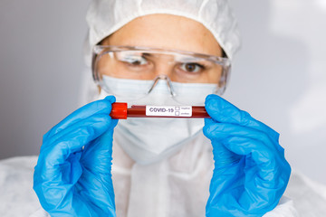 Covid 19 Coronavirus infected blood in tube in hand of scientist female doctor biohazard protection clothing in coronavirus research laboratory. Coronavirus Covid-19 vaccine research