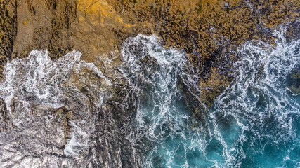 Waves of turquoise water washed by the rocky stone coast of Portugal. Aerial view.