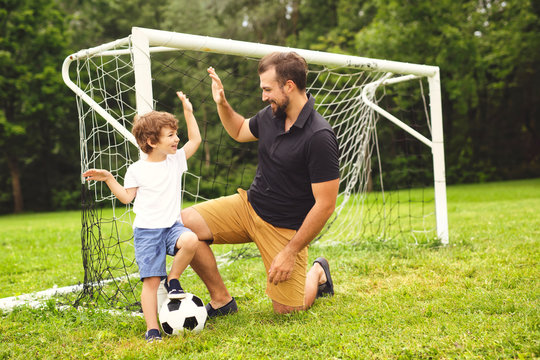 Image of family, father and son playing ball in the park