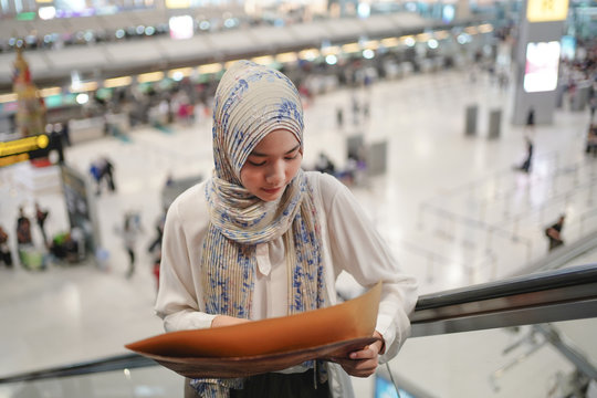 Asian muslim passenger travel tourist looking on the map to get the direction of destination way when she arrived at Airport. travel and tourism concept.    