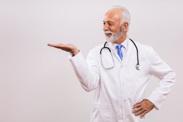 Portrait of senior doctor gesturing on gray background.