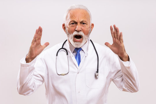 Image of  angry senior doctor shouting  on gray background.