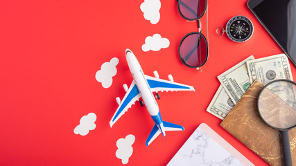 Travel and vacation. Red background, summer mood. Airplane, compass and passport with money. With space for design. Agency tour