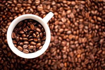 White cup with coffee beans on a background of coffee beans