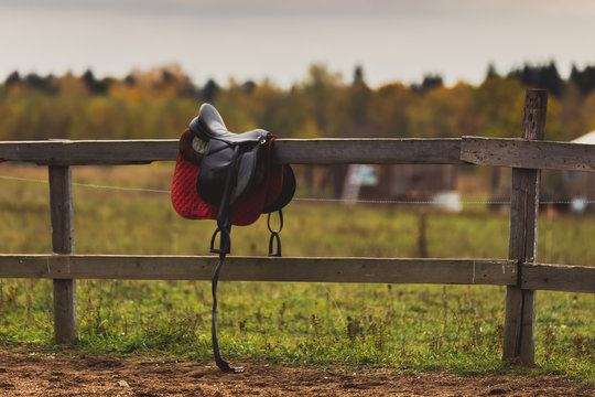 A saddle hangs on a wooden fence
