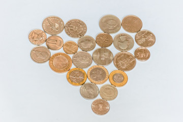 Assorted coins, both old ones which are no longer in circulation and contemporary ones which are used today, of various countries and currencies, laid out in a shape of a heart