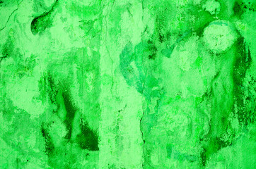 Green background. Wall with peeling plaster, tinted in green. Modern urban building concept. Bright neon backdrop. Selective focus