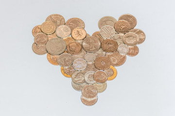 Assorted coins, both old ones which are no longer in circulation and contemporary ones which are used today, of various countries and currencies, laid out in a shape of a heart