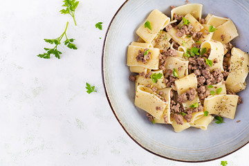 Pasta Calamarata with minced meat in blue bowl. Italian cuisine. Top view, overhead