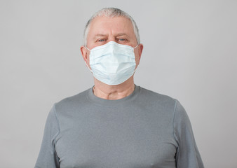 Senior in medical mask isolated on gray background