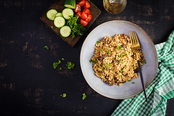 Bulgur pilaf with meat and and vegetables. Delicious healthy warm lunch on black background. Eastern cuisine. Top view, overhead, flat lay