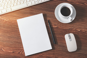 On the wooden table is an empty Notepad with a pen next to a keyboard, mouse, and a Cup of coffee