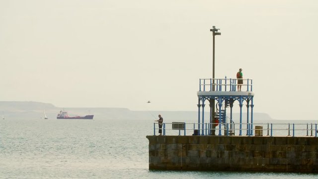 Fisherman and sightseer on pier