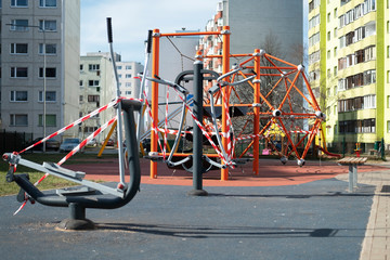 Coronavirus COVID-19 restriction. No people due to quarantine. Closed children's playground in the city. Empty park and playground. Stay at home compaign. Red warning tape on swings and slides