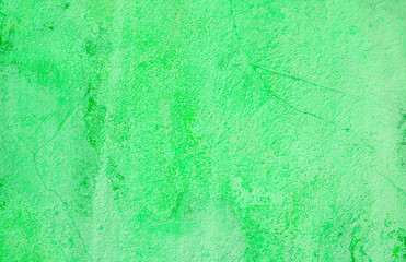 Green background. Wall with peeling plaster, tinted in green. Modern urban building concept. Bright neon backdrop. Selective focus