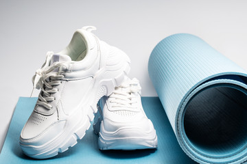 a pair of white sneakers sit on a blue yoga mat