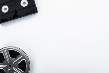 top view of old VHS cassette and film reel on white background