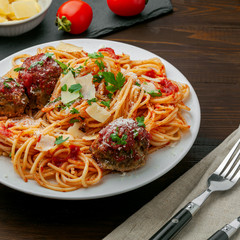 Italian meal made of pasta on a wooden table. Plate of traditional American spaghetti with meatballs and tomato sauce.
