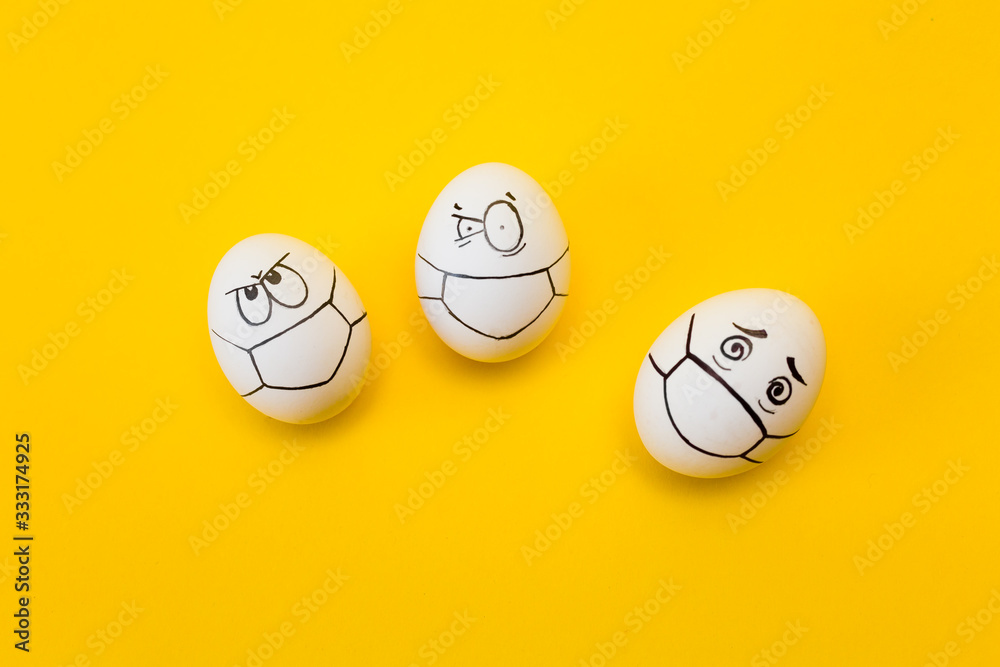 Wall mural drawing faces with medical masks on eggs isolated on yellow background