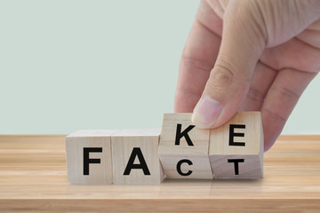 Hand flip wood cube change the word Fact or Fake. April fools day concept.