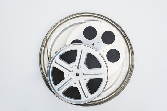 top view of film reels with film strip in tin case on white background