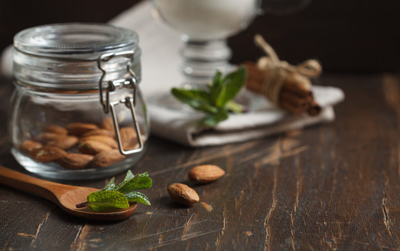 Almonds In A Small Glass Jar Close Up And A Glass Of Milk On A Dark Background