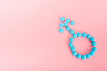 Top view of male sign from hormonal pills on pink background
