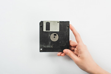 partial view of man holding black diskette on white background