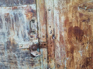 Texture of the old iron door with icing paint in overcast weather. Background of rusty iron