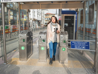Beautiful young girl uses metrocard to pay the commuter fare and enter turnstile in transit system in Istanbul,Turkey.Traveler woman lifestyle Concept.
